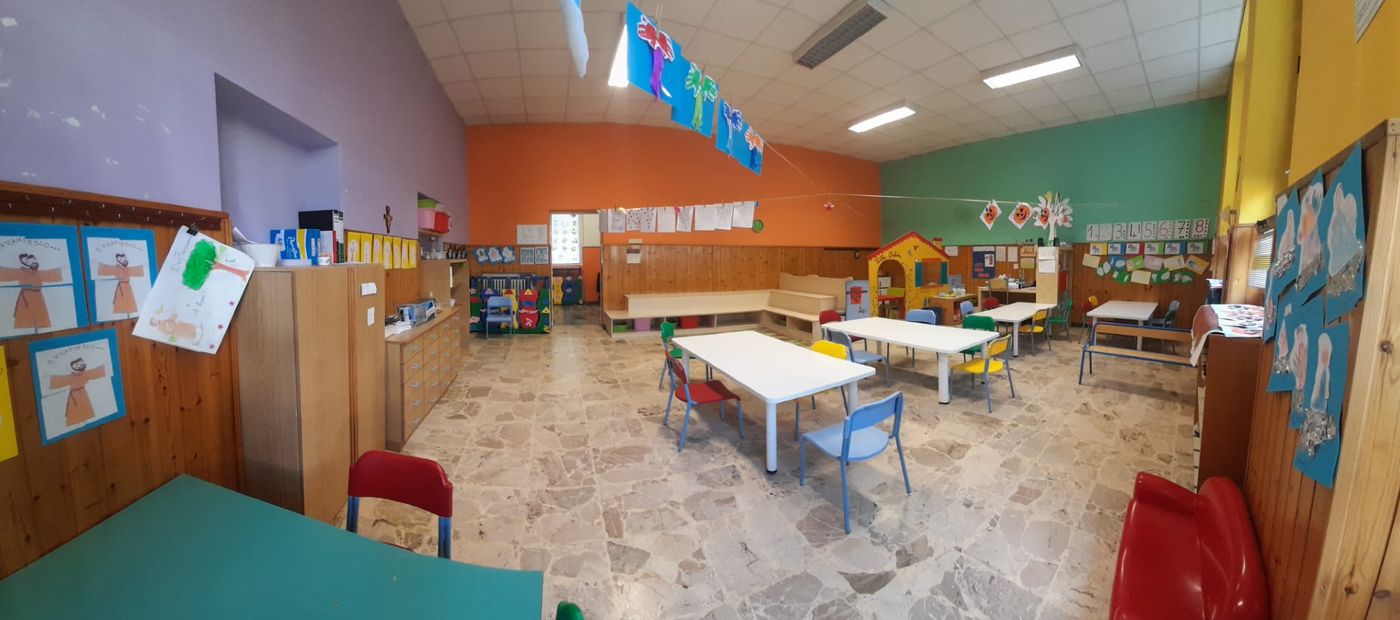 Una sezione della scuola, con i tavoli, gli angoli di gioco e i lavori dei bambini alle pareti