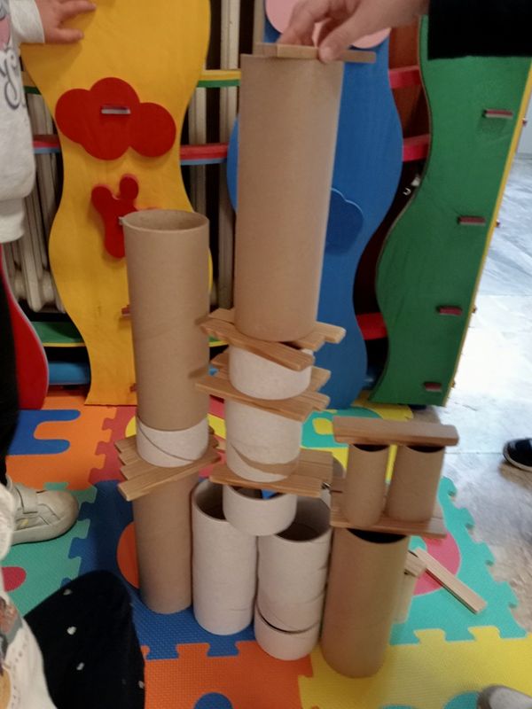 Una torre di tubi di cartone e legnetti costruita dai bambini sul tappeto della sezione